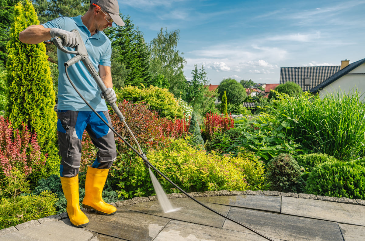 Professional pressure washing patio with green surroundings