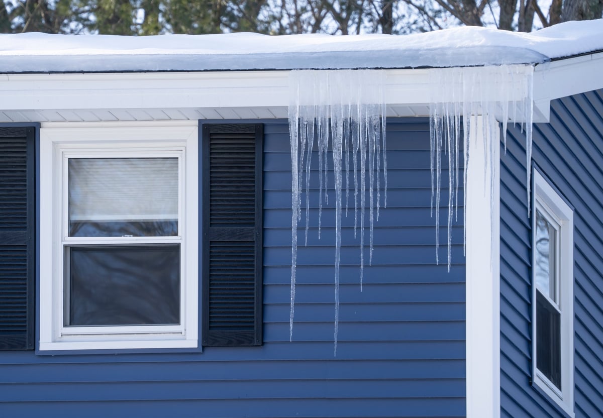 Ice dam on residential roof with icicles in winter