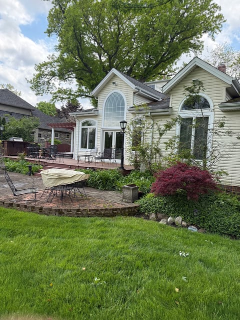Modern white house with arched windows, patio area, landscaped yard with red maple tree and manicured lawn