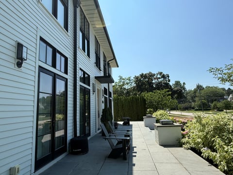 Modern white house with patio terrace overlooking landscaped garden under clear blue sky